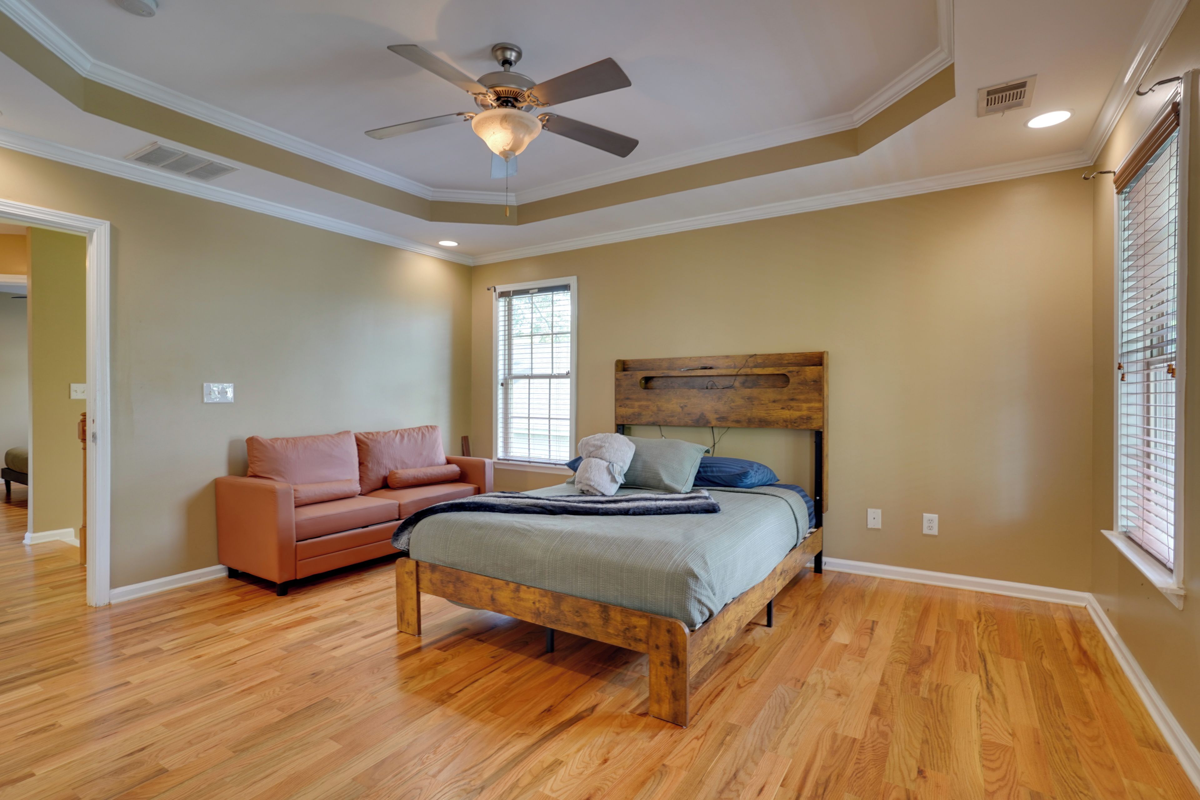 A bedroom with a bed, a wooden headboard, a ceiling fan, and a window.