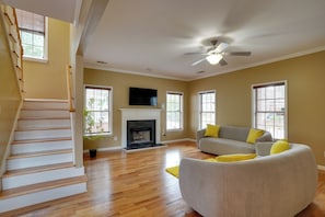 A spacious living room with a fireplace, a sofa, and a staircase. - 3 Mi to Mercedes-benz Stadium! Group Getaway (Austin)