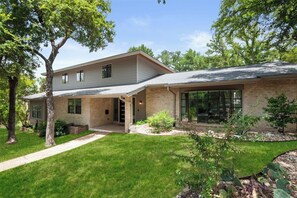 A two-story house with a brick exterior, large windows, and a well-maintained lawn.
