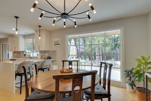 A modern kitchen with a central island, pendant lighting, and large windows.