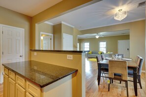 A kitchen with a granite countertop and a dining area with a wooden table and chairs.