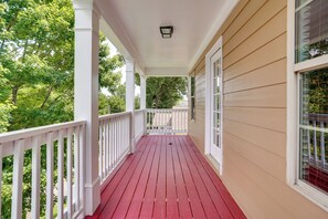 A covered porch with a red floor, white railings, and beige siding.