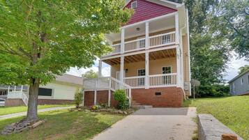 A two-story building with a covered porch and a brick foundation.