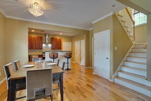 A spacious dining area with a wooden table and chairs, a kitchen with wooden cabinets and a chimney, and a staircase leading to another level. - 3 Mi to Mercedes-benz Stadium! Group Getaway (Austin)
