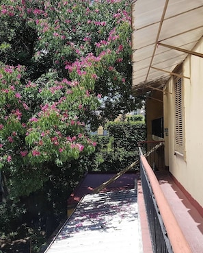 A covered outdoor area with a metal staircase leading down, surrounded by greenery and a building with a beige facade. - Hotel Histórico San Telmo (Buenos Aires)