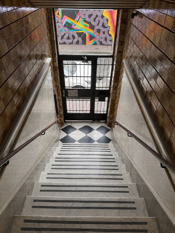 A staircase with a geometric patterned floor, metal railings, and a door with barred windows.