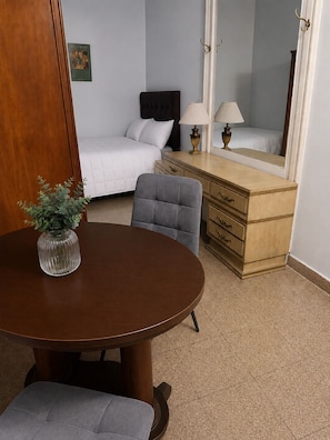 A hotel room with a bed, a dresser, a mirror, a table with a vase, and a chair. - Hotel Histórico San Telmo (Buenos Aires)