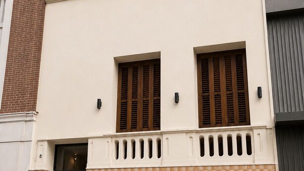 Ein zweistöckiges Gebäude mit einer Schachbrett-Fassade, einer schwarzen Tür und zwei Fenstern mit Fensterläden.