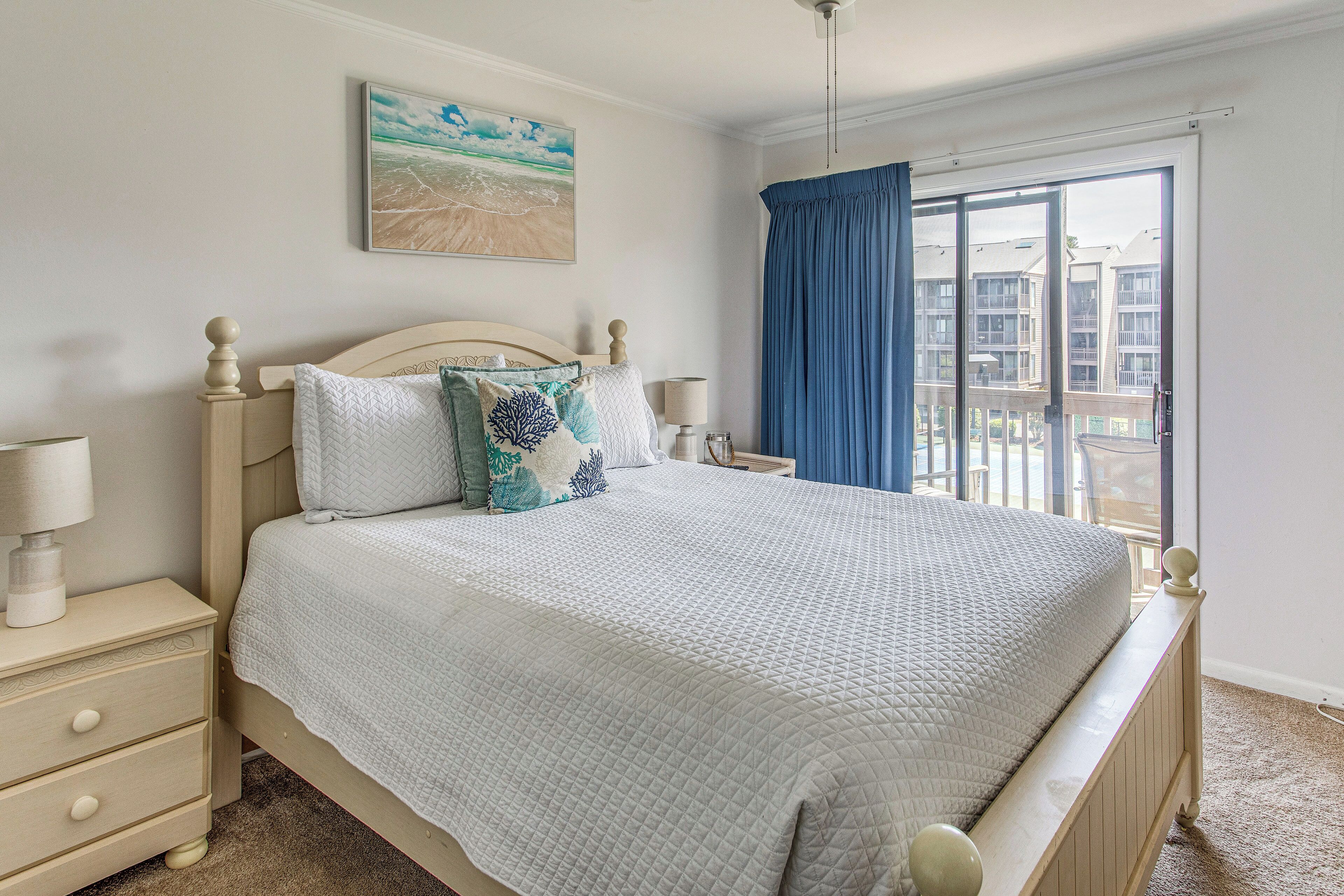 A bedroom with a bed, bedside tables, a nightstand, a window with curtains, and a painting on the wall.