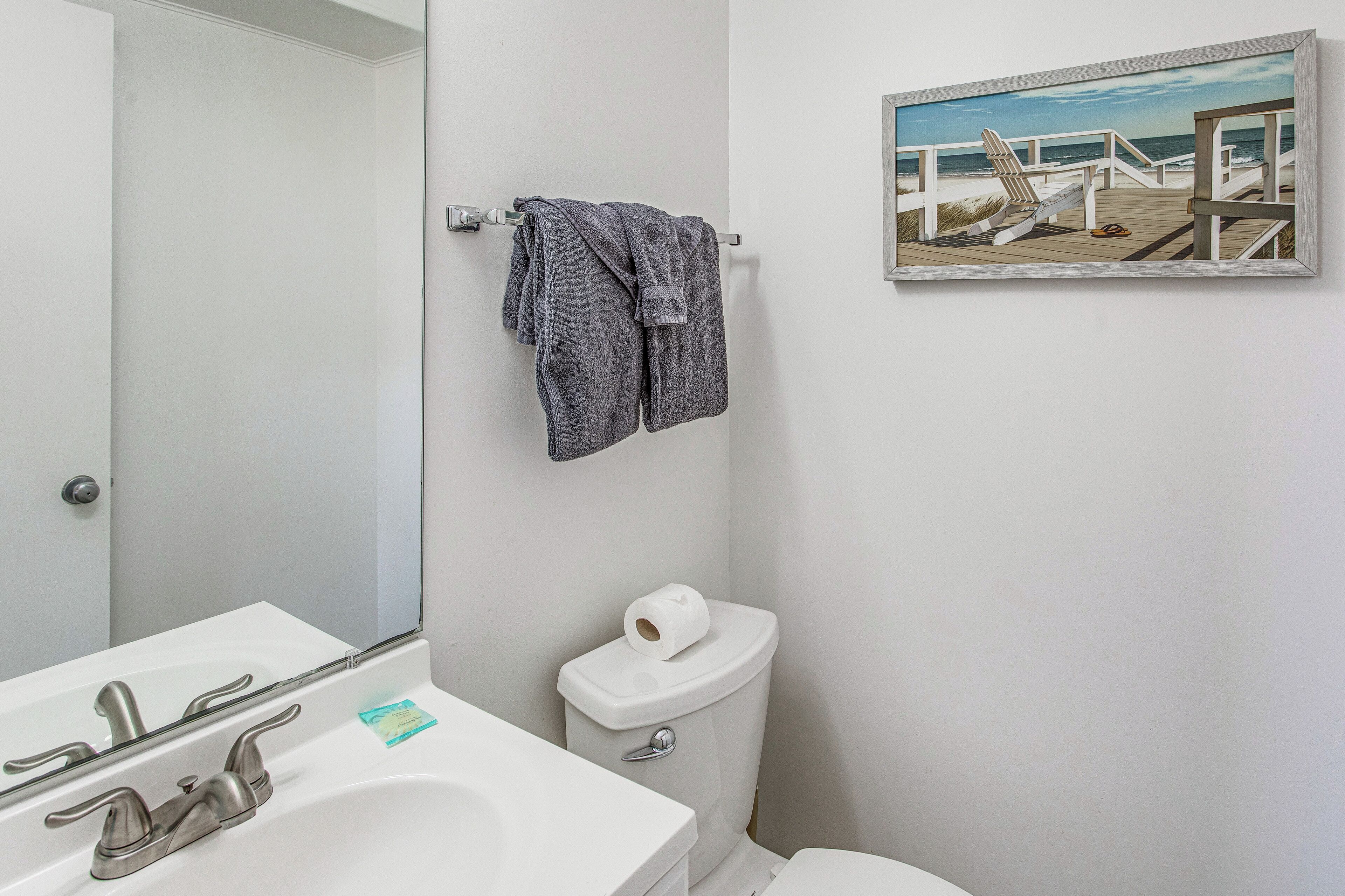 Et badeværelse med en hvid vask, toilet og et håndklædestativ med to håndklæder.
