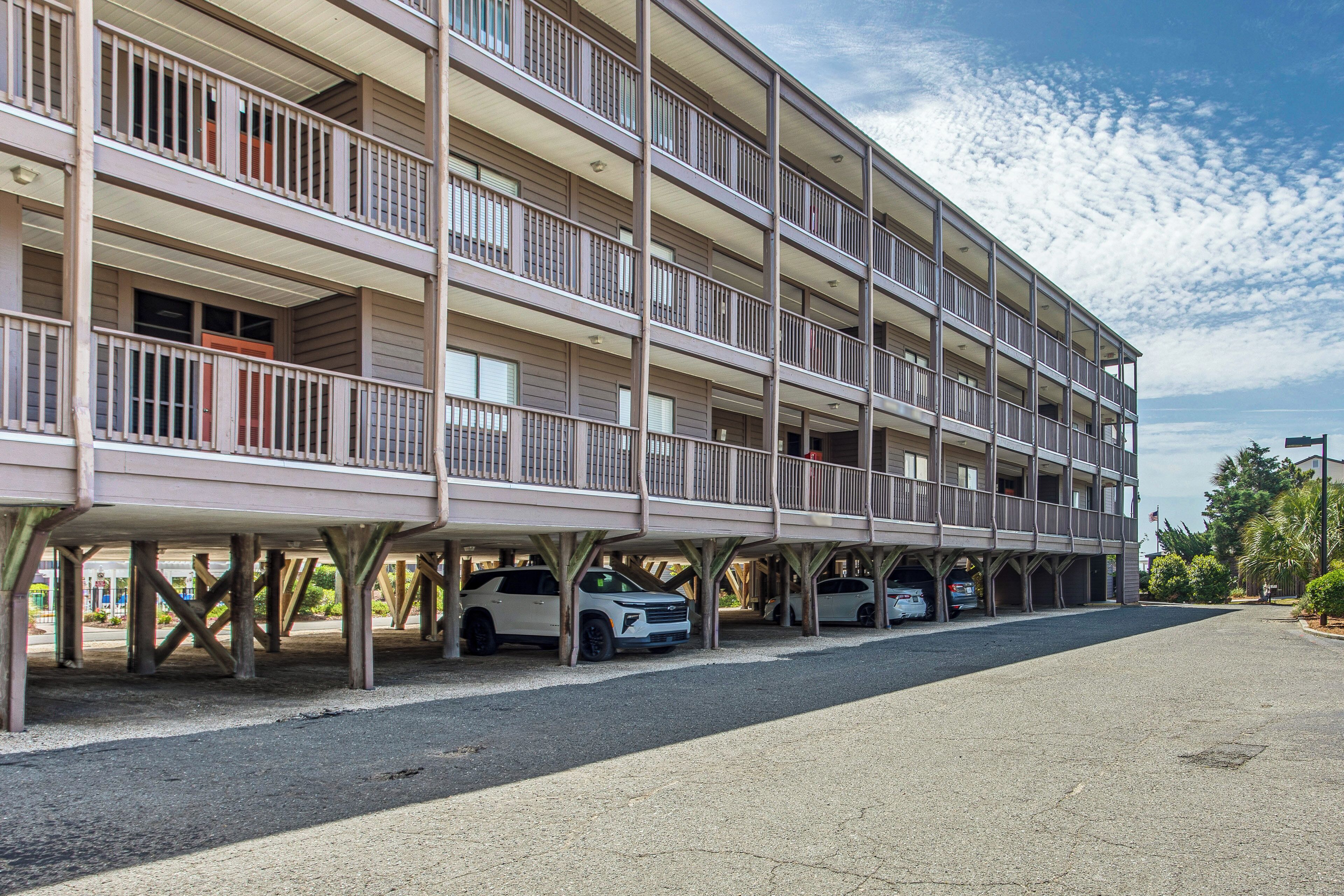 Un edificio de varios pisos con balcones, espacios de estacionamiento y cielo despejado.