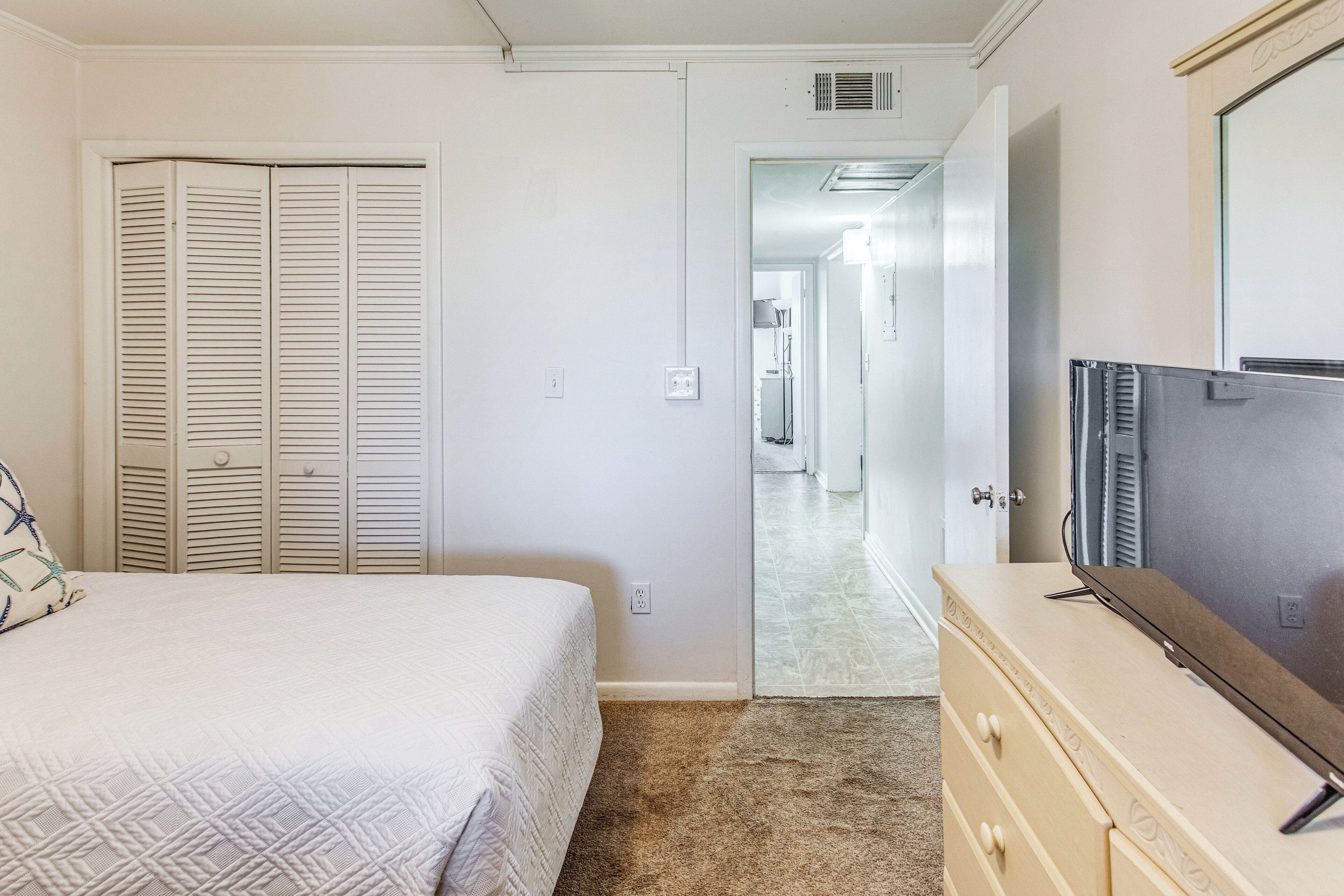A bedroom with a bed, a dresser, a TV, and a closet.