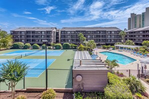 Ein Hotel mit mehreren Tennisplätzen, einem Schwimmbad und einer überdachten Sitzgelegenheit.