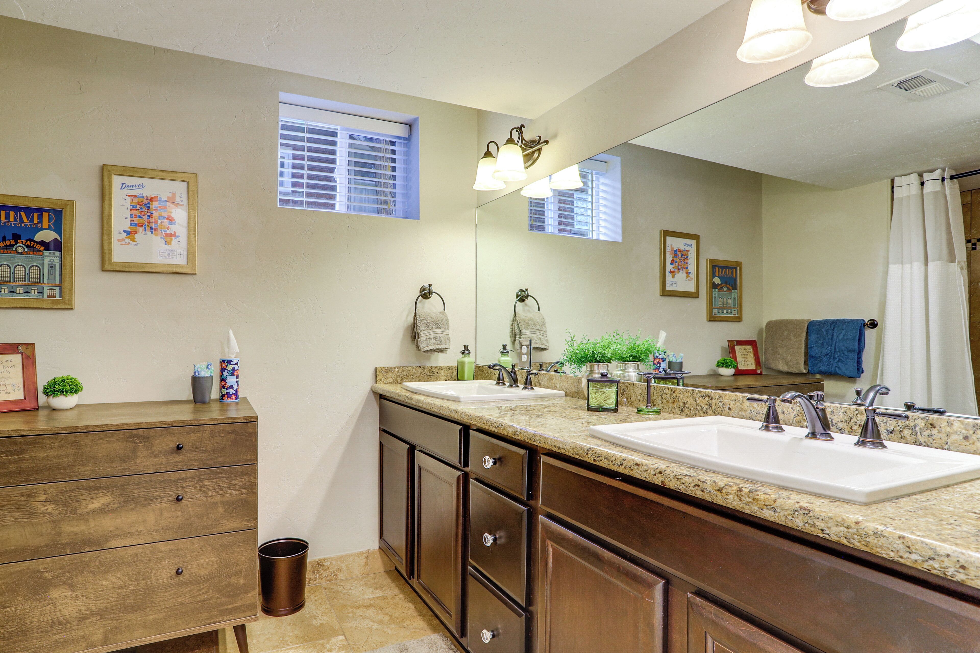 A bathroom with two sinks, a mirror, a wooden cabinet, and a window with blinds.
