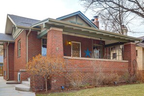 A brick building with a porch, a star decoration, and a tree in front.