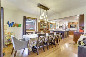 A spacious kitchen with wooden cabinets, a dining area with a table set for six, and a bar area. - Explore Denver! Welcoming Home w/ Porch & Yard (Denver)