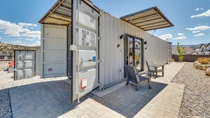 A portable container with a door, a bench, and a small patio area with gravel. - Mtn Views & Trail Access! 2-unit Cedar City Escape (Cedar City)