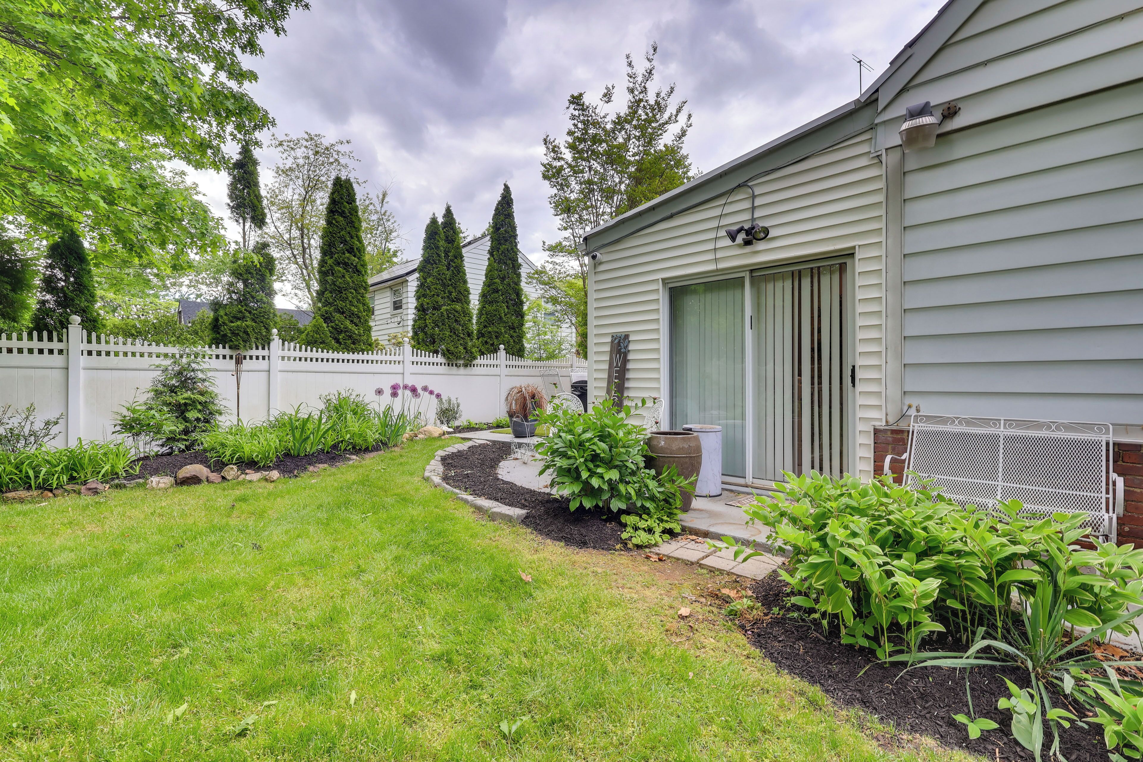 A residential property with a well-maintained lawn, a white picket fence, and mature trees.