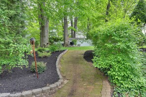 A brick pathway leading through a garden with trees and a bird feeder. - Retreat w/ Yard Near NYC & Metlife Stadium! (Teaneck)