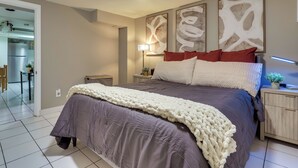 A bedroom with a large bed, a bedside table, a lamp, and abstract wall art. - Retreat w/ Yard Near NYC & Metlife Stadium! (Teaneck)