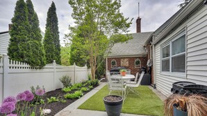A backyard with a lawn, potted plants, a patio table, and a white fence. - Retreat w/ Yard Near NYC & Metlife Stadium! (Teaneck)