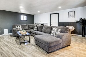 A modern living room with a sectional sofa, a coffee table, and a dark wall.