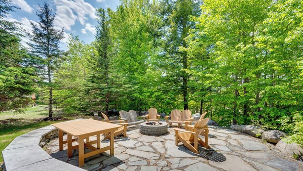 An outdoor patio with stone flooring, wooden furniture, and a fire pit. - Riverfront Ski-in/ski-out Condo at Loon Mountain (Lincoln)