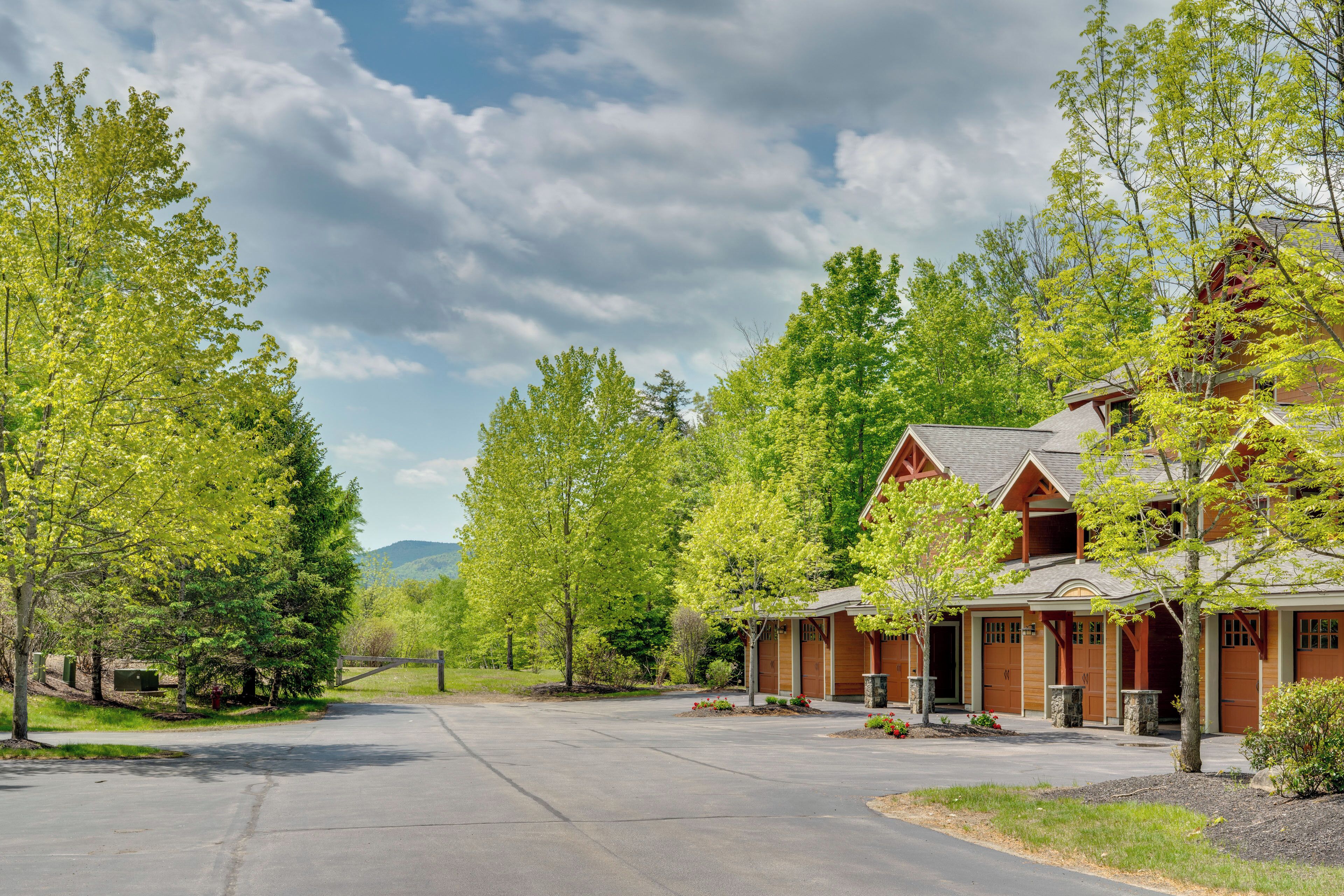 A residential area with a large house featuring a garage, a driveway, and a well-maintained lawn.