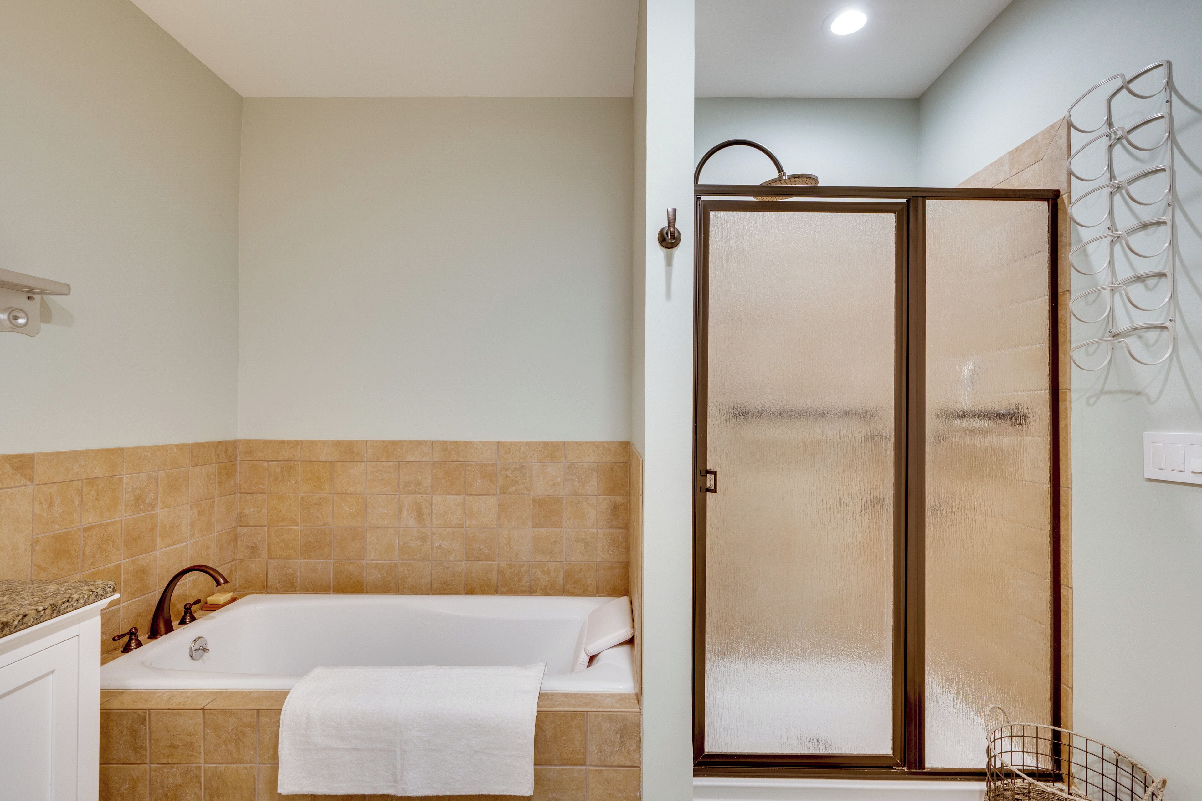 A bathroom with a bathtub, a shower with a glass door, and a towel rack.