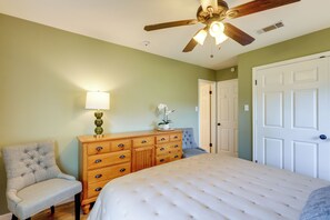 Un dormitorio con cama, cómoda, silla, ventilador de techo y puerta.