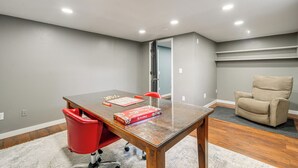 A room with a wooden table, a red chair, a beige chair, and a game board. - Spacious Home: Private Deck 4 Mi to Dtwn Fargo (Moorhead)
