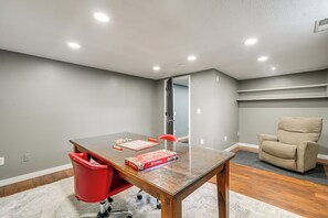 Une piÚce avec une table en bois, une chaise rouge, une chaise beige et un jeu de société.