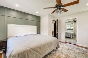 Une chambre Ă coucher avec un lit, un ventilateur de plafond et une porte donnant sur une autre piĂšce.