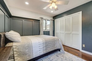 A bedroom with a bed, a ceiling fan, a window with curtains, and a closet.