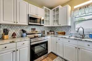 A kitchen with white cabinets, a microwave, stove, and a window with a view. - Family Home in Heart of Brownsville: Walk to River (Brownsville)