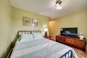 Une chambre à coucher avec un lit, une télévision, une commode et deux tableaux encadrés accrochés au mur.