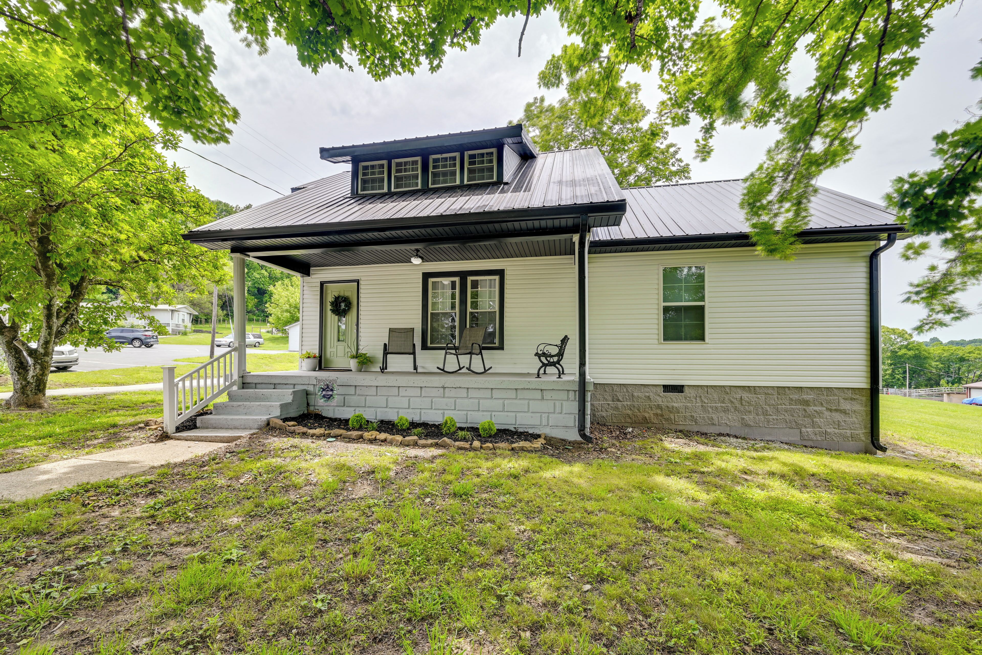 A single-story house with a porch, a small front yard, and a tree in the background.