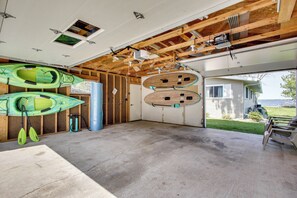 An open garage with kayaks and paddleboards, a concrete floor, and a view of a house and yard. - Lakefront Family Home w/ Dock & Views in Cecil! (Cecil)