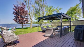 A deck with outdoor furniture, a covered seating area, and a grill.