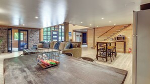 Amplia sala de estar con una mesa de comedor de madera, un sofá y una zona de cocina con microondas.