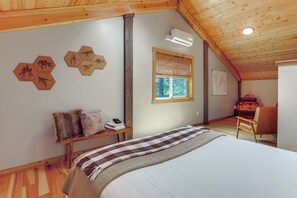 A bedroom with a bed, a wooden bench, a window, and a wall-mounted air conditioner.