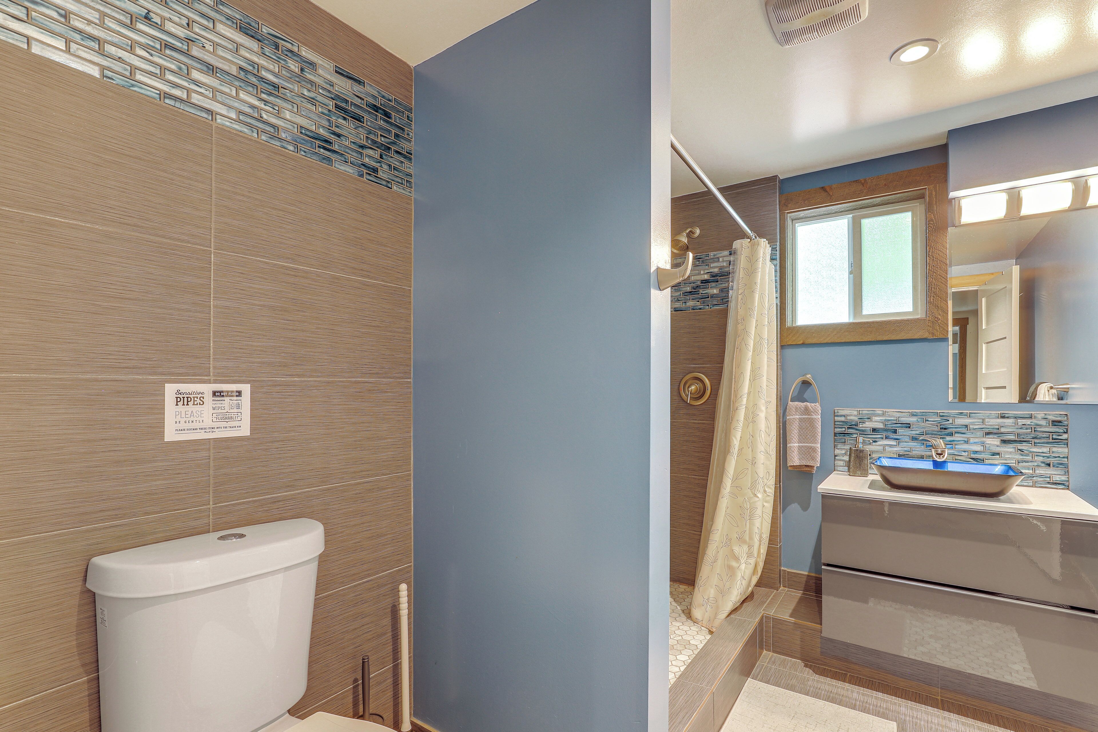 A bathroom with a toilet, sink, shower, and a sign on the wall.