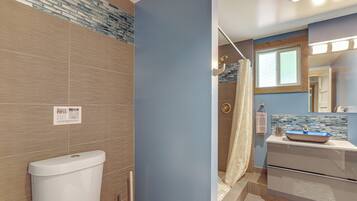 A bathroom with a toilet, sink, shower, and a sign on the wall.