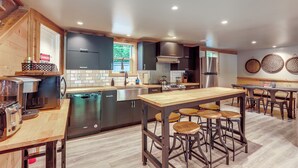 Una cocina moderna con una isla central, taburetes de bar y electrodomésticos de acero inoxidable.