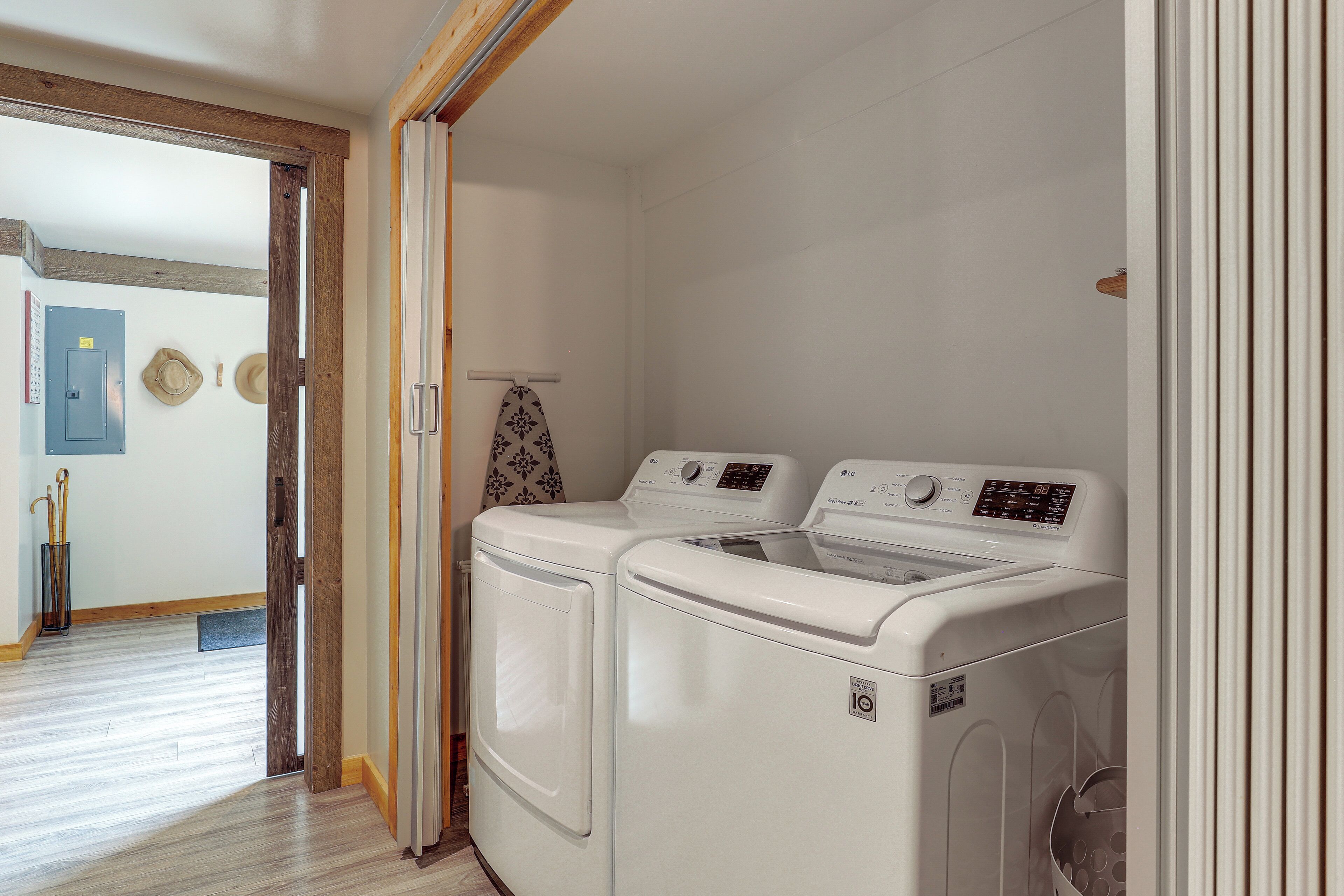 A laundry room with two stacked front-loading washing machines, a wooden door frame, and a hallway leading to another room.