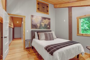 A bedroom with a bed, a painting, a window, and a door. - Jurassic Retreat: Hot Tub & Life-size Dinosaurs! (Washougal)