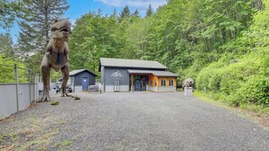 Un edificio con camino de grava, área cercada y una gran estatua de dinosaurio.