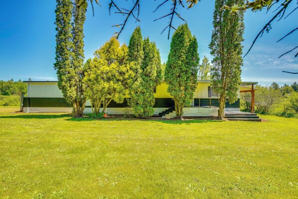 Una casa moderna con césped verde, un porche cubierto y una escalera que lleva a una terraza.