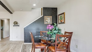 A dining area with a round table, wooden chairs, a black accent wall, and a staircase. - Triple-unit Galt Escape Near Lodi Vineyards! (Galt)
