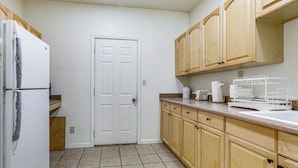 A kitchen with wooden cabinets, a white refrigerator, a sink, and a door. - Triple-unit Galt Escape Near Lodi Vineyards! (Galt)